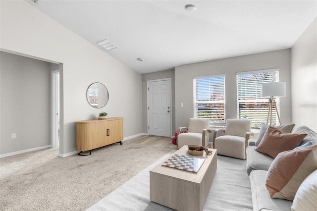 living area featuring light carpet, visible vents, baseboards, and vaulted ceiling