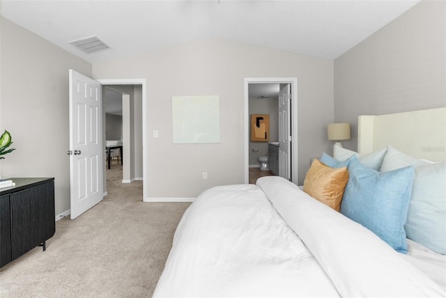 bedroom featuring light carpet, baseboards, visible vents, lofted ceiling, and ensuite bath