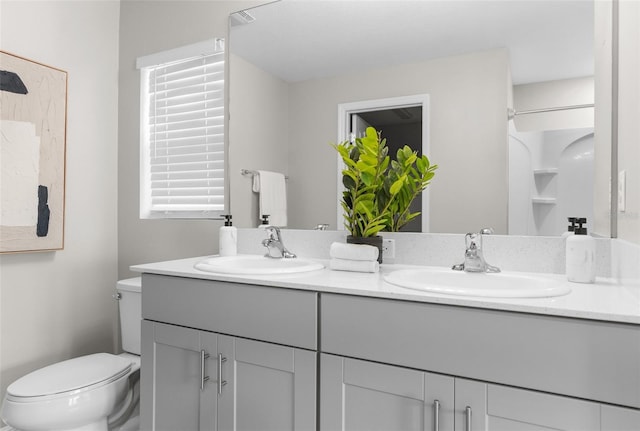 full bathroom featuring double vanity, a sink, and toilet