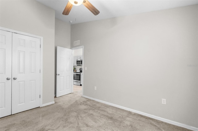 unfurnished bedroom featuring baseboards, visible vents, light colored carpet, vaulted ceiling, and a closet