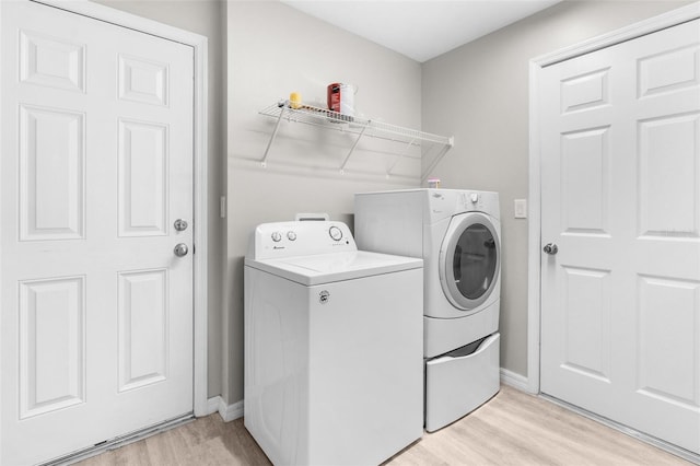 clothes washing area featuring baseboards, laundry area, light wood-style floors, and washer and dryer