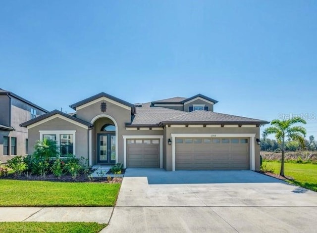 view of front of house with an attached garage, a front yard, concrete driveway, and stucco siding