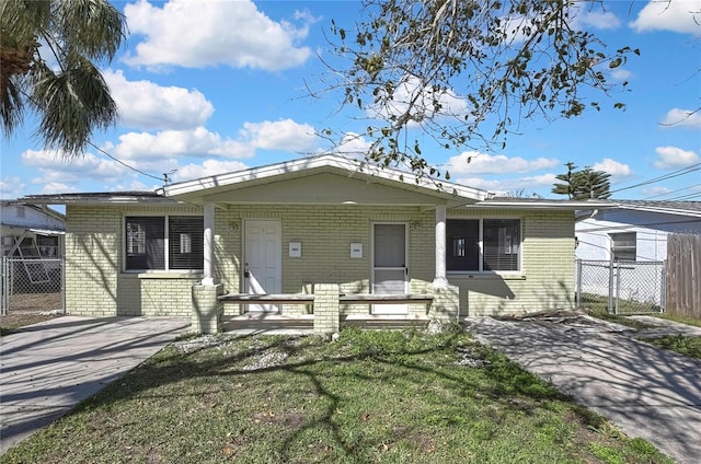 view of front of home featuring driveway, fence, a front lawn, and brick siding