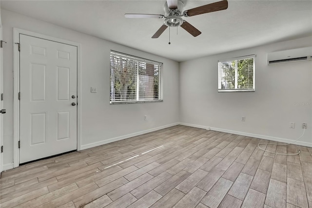 unfurnished room with ceiling fan, a wall mounted AC, light wood-style flooring, and baseboards