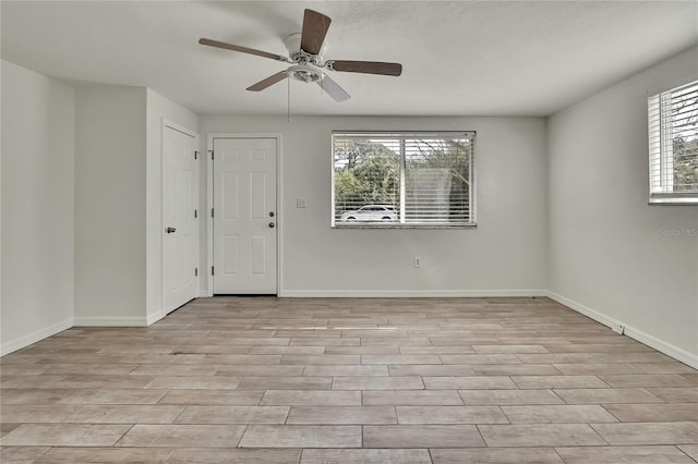 spare room featuring ceiling fan, light wood-style flooring, and baseboards