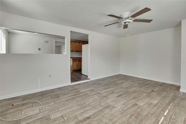 spare room featuring light wood finished floors, ceiling fan, and baseboards