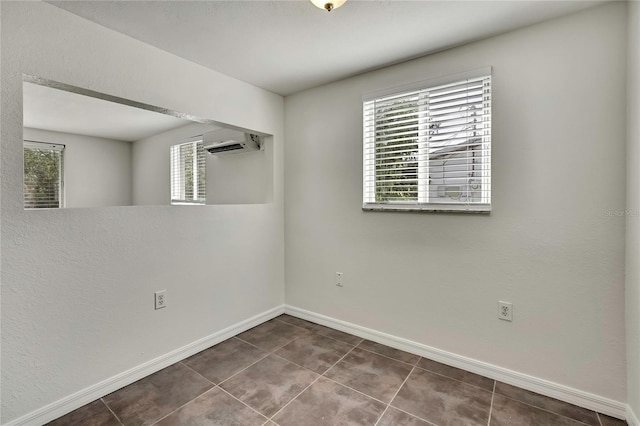 spare room featuring a wall unit AC, tile patterned floors, and baseboards