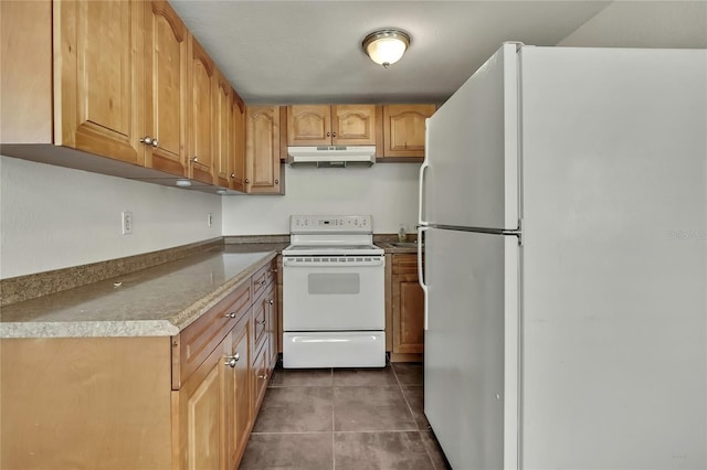 kitchen with white appliances, dark tile patterned floors, and under cabinet range hood