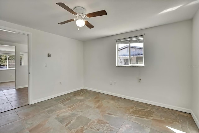 spare room featuring a healthy amount of sunlight, ceiling fan, and baseboards