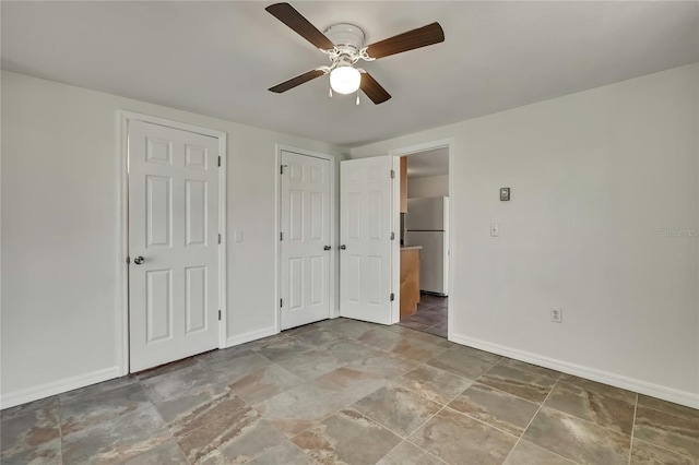 unfurnished bedroom featuring ceiling fan, freestanding refrigerator, and baseboards