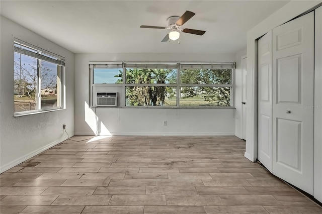 interior space with cooling unit, ceiling fan, baseboards, and wood finished floors