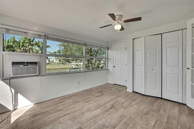 unfurnished bedroom with a closet, light wood-style flooring, ceiling fan, cooling unit, and baseboards