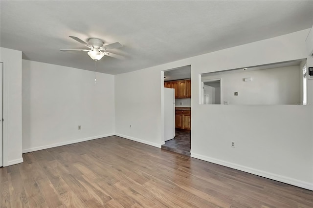 unfurnished living room with baseboards, a ceiling fan, and wood finished floors