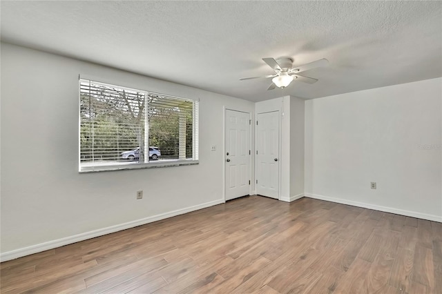 spare room with a ceiling fan, a textured ceiling, baseboards, and wood finished floors