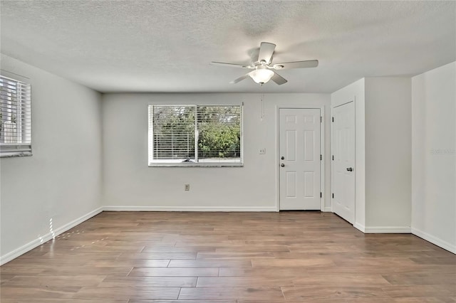 spare room featuring ceiling fan, a textured ceiling, wood finished floors, and baseboards