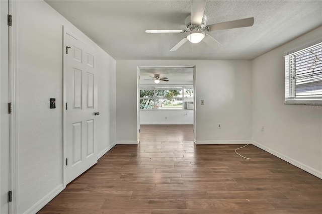 empty room featuring a textured ceiling, ceiling fan, wood finished floors, and baseboards