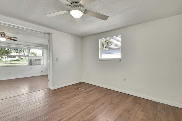 unfurnished room with a wealth of natural light, a textured ceiling, and wood finished floors