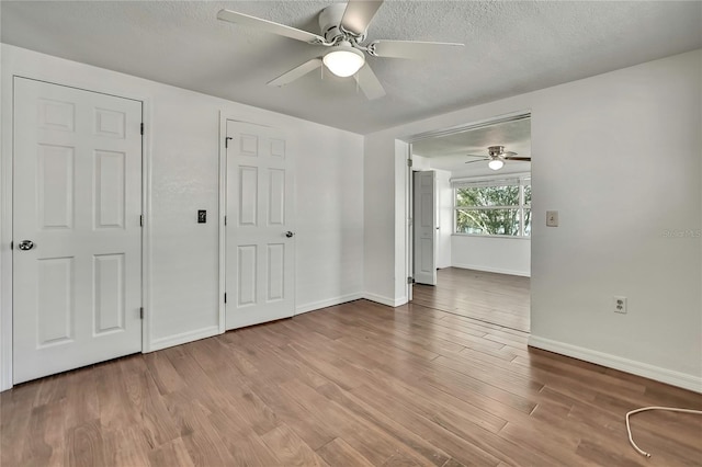 spare room with a textured ceiling, baseboards, and wood finished floors