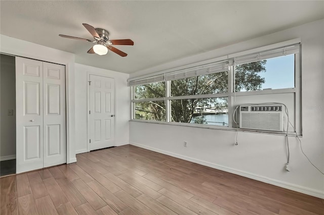 unfurnished bedroom with baseboards, a ceiling fan, wood finished floors, cooling unit, and a closet