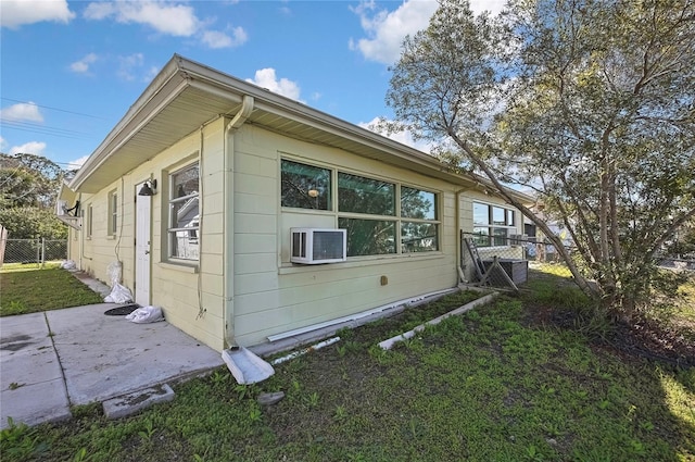 view of side of home featuring a patio area, fence, cooling unit, and a yard