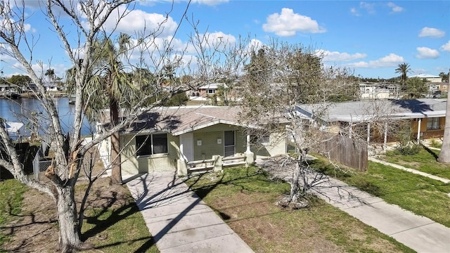 view of front of home with brick siding, roof with shingles, fence, a residential view, and a front lawn