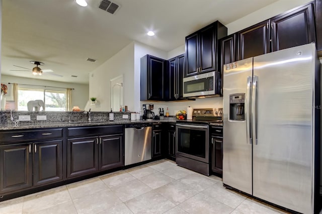 kitchen featuring dark stone counters, stainless steel appliances, a sink, and visible vents