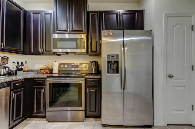 kitchen with appliances with stainless steel finishes, dark stone countertops, and light tile patterned floors