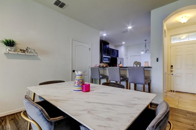 dining room featuring arched walkways, wood finished floors, visible vents, and recessed lighting