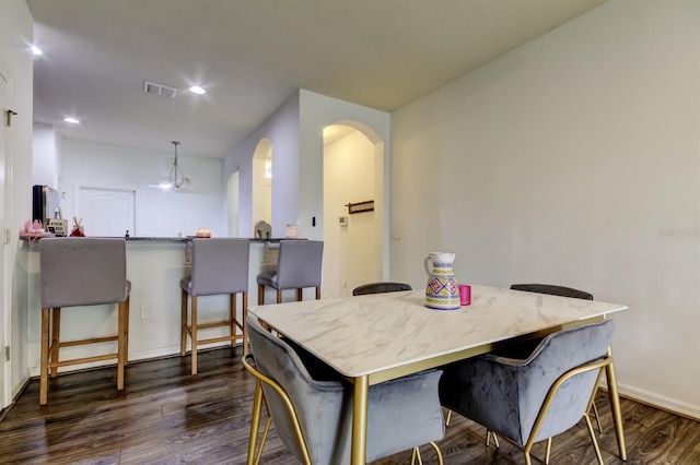 dining room featuring arched walkways, recessed lighting, dark wood-type flooring, visible vents, and baseboards