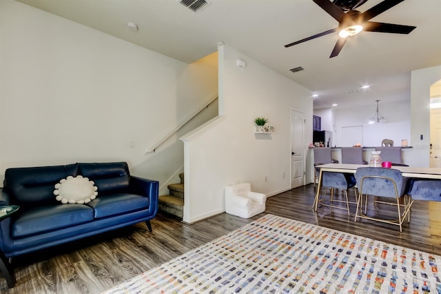 living room with a ceiling fan, stairs, visible vents, and wood finished floors