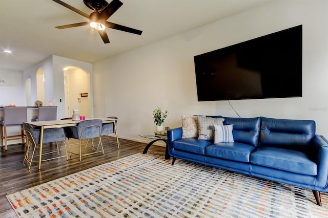 living room with arched walkways, ceiling fan, baseboards, and wood finished floors