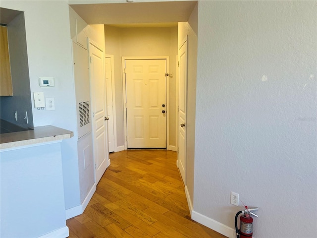 hallway with light wood-type flooring and baseboards