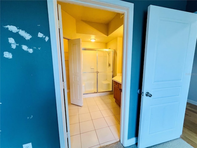 bathroom with tile patterned flooring, baseboards, a shower stall, and vanity