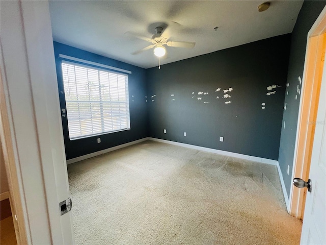 carpeted empty room with ceiling fan and baseboards