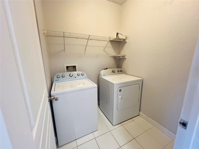 laundry room featuring washing machine and dryer, laundry area, baseboards, and light tile patterned floors