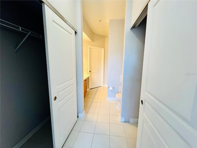 corridor with light tile patterned flooring and baseboards