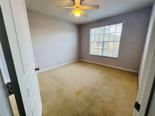 spare room with carpet, baseboards, and a ceiling fan