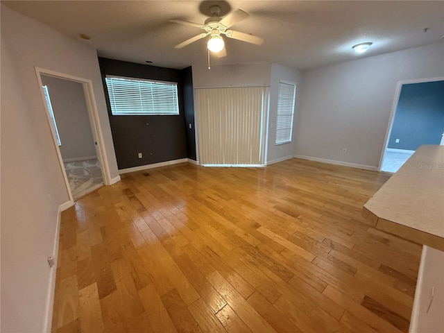 unfurnished living room featuring light wood-style flooring, ceiling fan, and baseboards