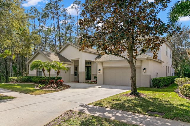 view of front of home featuring a garage, driveway, a front lawn, and stucco siding