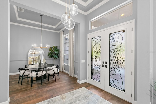 foyer with ornamental molding, a raised ceiling, french doors, and wood finished floors