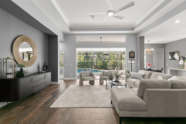 living room with a sunroom, a tray ceiling, dark wood-style flooring, and crown molding