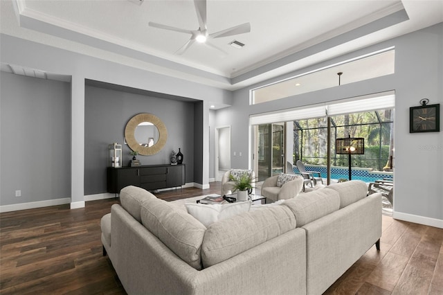 living area featuring visible vents, dark wood finished floors, baseboards, a sunroom, and a tray ceiling