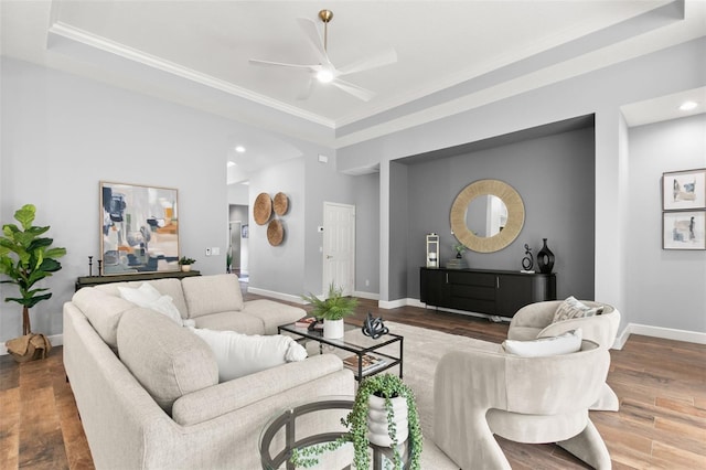 living room with a ceiling fan, a raised ceiling, baseboards, and wood finished floors