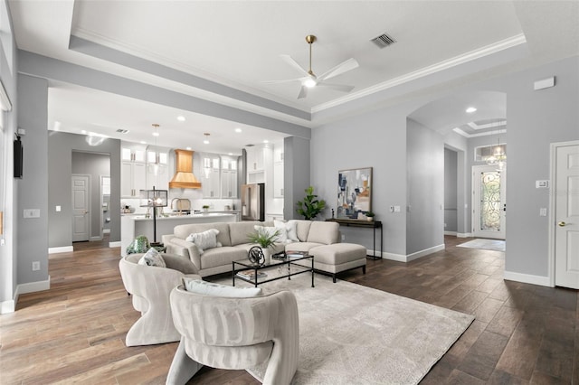 living room featuring crown molding, baseboards, a raised ceiling, and wood finished floors