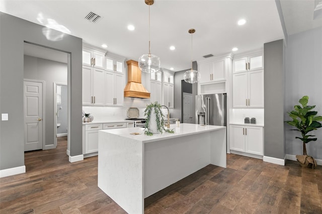 kitchen featuring white cabinets, premium appliances, custom range hood, glass insert cabinets, and light countertops