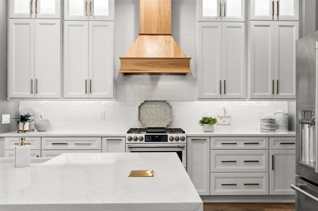 kitchen featuring premium appliances, white cabinetry, backsplash, and custom exhaust hood