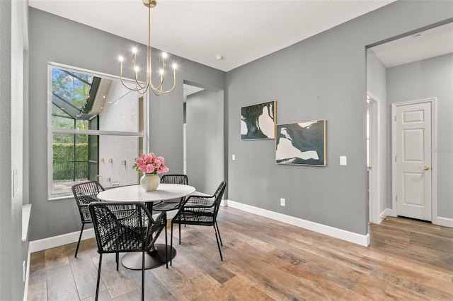 dining room featuring a notable chandelier, baseboards, and wood finished floors