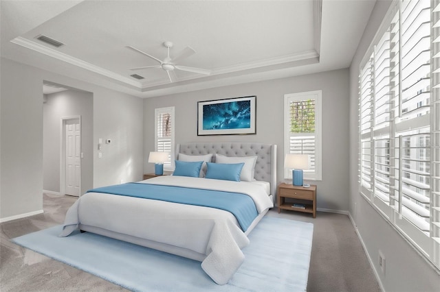 carpeted bedroom featuring a tray ceiling, visible vents, a ceiling fan, ornamental molding, and baseboards