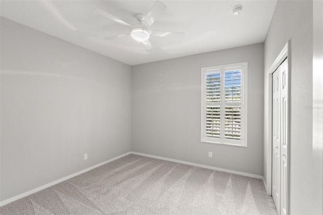 unfurnished bedroom featuring ceiling fan, a closet, carpet, and baseboards