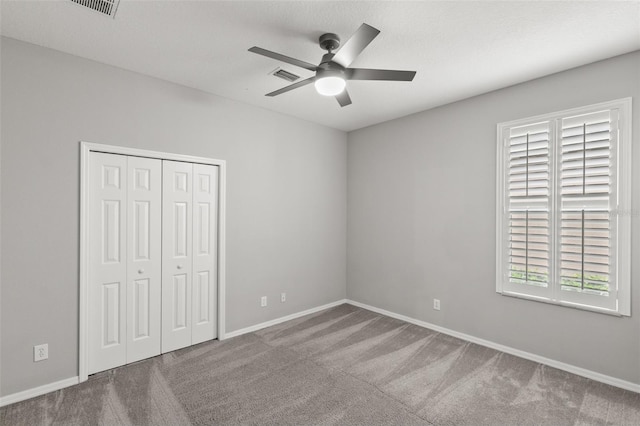 unfurnished bedroom with carpet, baseboards, ceiling fan, and a closet